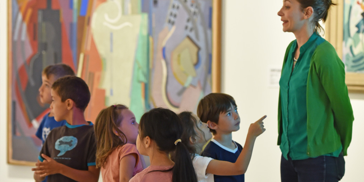 Médiatrice culturelle s'exprimant devant des jeunes visiteurs, dans une exposition