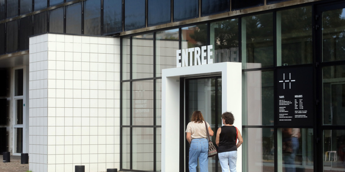 Deux visiteurs devant l'entrée du MAMC+