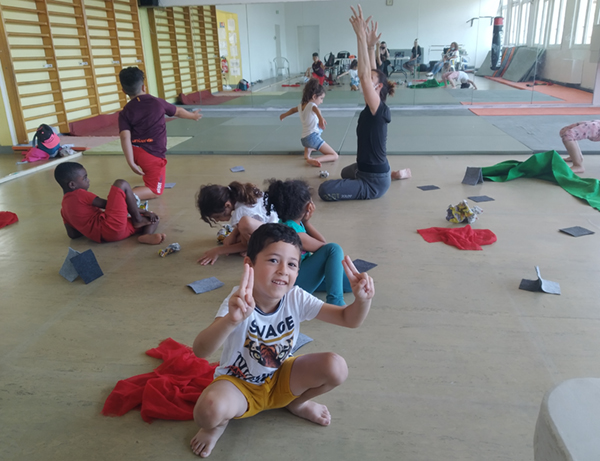 Vue d'ensemble de l'atelier de danse, les enfants prennent la pose, au premier plan un petit garçon nous sourit/